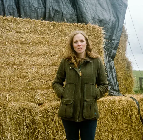 Joanne Coates Debbie, a farmer's wife, stands next hay bales on her farm near Otterburn in Northumberland