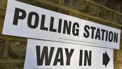 PA Media A sign on a wall points to the entrance of a polling station for the London mayoral elections