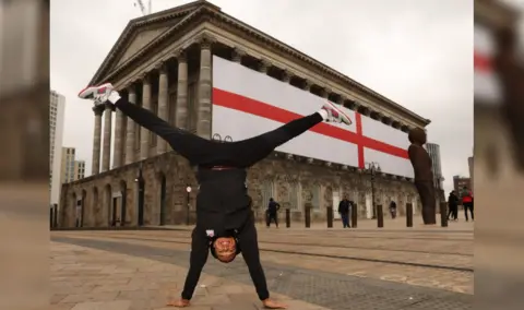 Birmingham City Council Joe Fraser doing a handstand in front of the flag