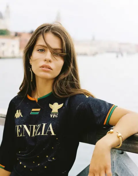 Kappa Promotional photograph showing a woman modelling the 2021/22 Venezia shirt with the city as a backdrop
