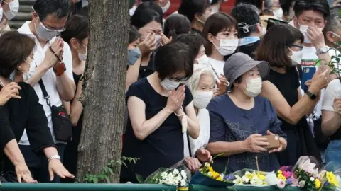 EPA People pray and cry as a hearse with the body of Shinzo Abe drives past them in Tokyo, Japan. Photo: 12 July 2022