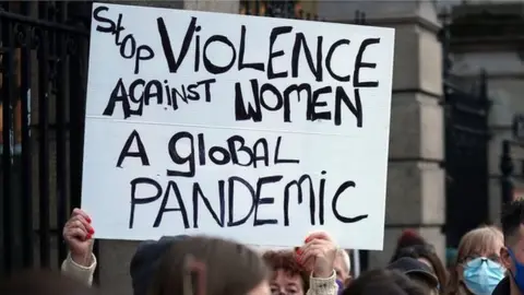 PA Media A protestor holding a sign that reads: Stop violence against woman - a global pandemic
