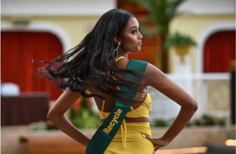 AFP Hiwot Yirga pictured with her hands on her hips. Her hair is swishing in the air. She is wearing a sash which says "recycle" on it.