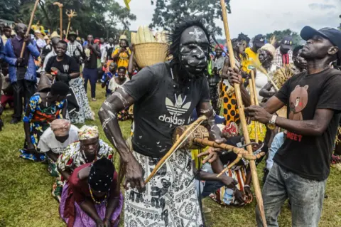 Getty Images A group of people dancing, some of whom are wearing traditional clothing. The man in the centre appears to be playing some sort of musical instrument and is wearing a mask.