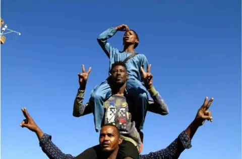 AFP A pyramid of three men making a peace sign against a clear blue sky
