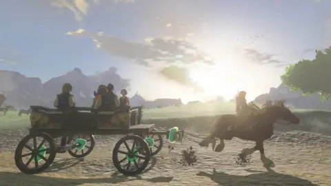 Nintendo Link, on his horse, pulls a carriage full of villagers along a dirt path. A green glow emanates from the carriage's wheels - showing the player that they have been attached by using the game's new Ultrahand ability