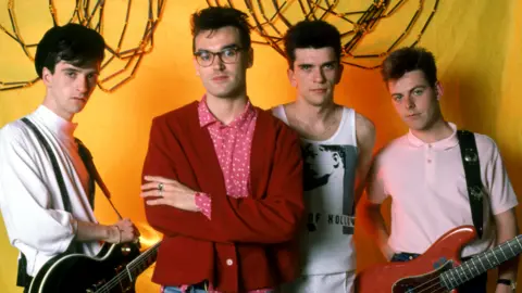 Getty Images Bassist Andy Rourke poses with other members of The Smiths, for a portrait ahead of their first show in Detroit during the 1985 Meat Is Murder Tour
