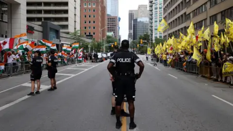 Getty Images Police officers stand guard as Pro-Khalistan supporters gather for a demonstration in front of the Indian Consulate in Toronto, Ontario, Canada on July 8, 2023. Pro-India counter protestors also gathered outside the Indian Consulate for a counter protest.