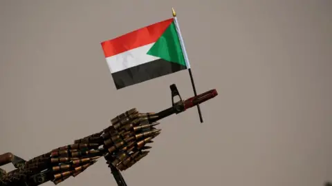 Reuters A Sudanese national flag is attached to a machine gun of Rapid Support Forces (RSF) soldiers in 2019