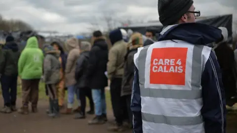 PA Media A general view of daily life in the Jungle refugee camp in Calais, France, with a worker wearing a Care4Calais top.