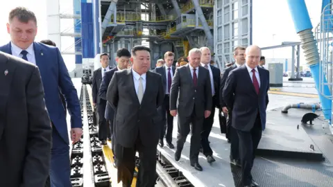 Reuters Kim Jong Un and Vladimir Putin are followed by their delegations as they tour a space launch site at Vostochny Cosmodrome on 13/9