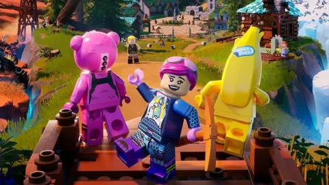 Lego/Epic Games A lego character with a smiling, cocky expression stands between a bright pink Lego bear and yellow, humanoid banana - the three are modelled on player characters from Fortnite. They're in a brightly coloured field, and the scene stretches out behind them, featuring Lego sheep grazing on grass, and structures including a church, castle and log cabin are visible. There's lots of activity going on - we can see characters chopping down trees and milling around the village in the distance.