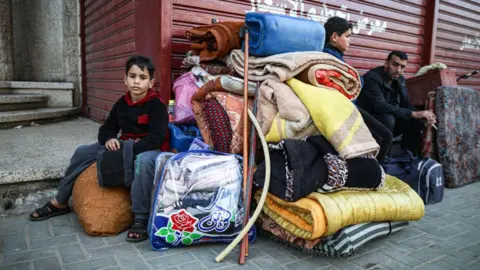 Getty Images Two children and a man are pictured with a pile of belongings in the street