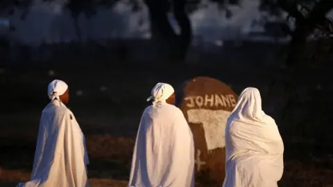 Reuters Three women in white kneeling down praying in Harare