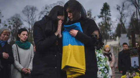 Getty Images Women crying at a cemetery in Lviv, March 2024