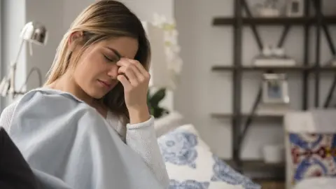 Getty Images Tired woman holding head