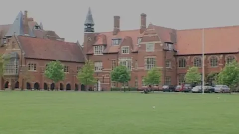 External view of Abingdon School - large red brick three-storey building with trees and lawn in front