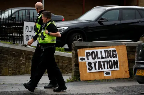 Reuters Police walk past a polling station in Bradford