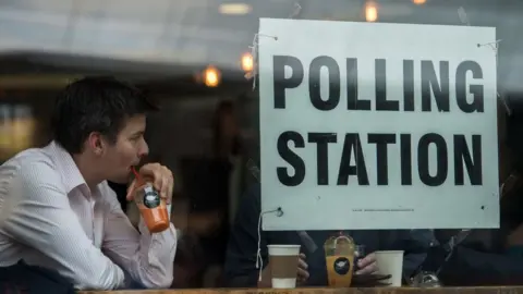 Getty Images A man drinks juice next to a sign in the window of a cafe in Borough