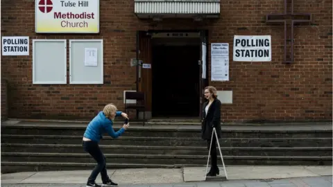 Getty Images A young woman has her photo taken outside a polling station at Tulse Hill Methodist Church