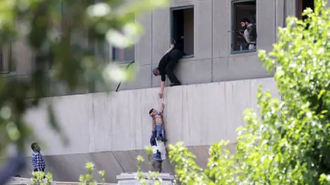 Getty Images A child is lowered from a window in the Iranian parliament building following an attack on 7 June 2017 in Tehran