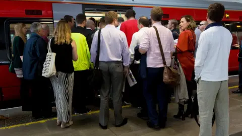 PA People queuing to get on a train