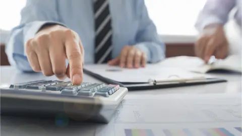 Getty Images Man punching numbers into calculator