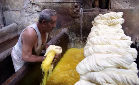 EPA Salama, 76, owner of the tannery, dyes white yarn rolls inside his tannery in Cairo, Egypt, 07 November 2017. Salama started working when he was seven years old during the reign of King Farouk over Egypt because, according to him, the police used to arrest unemployed males of all ages. Now, after almost 70 years, Salama"s tannery is the only one left in the old part of Cairo. The yarn produced is used for shoe laces, mattresses upholstery, ballet dance outfits, and suits.