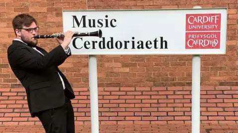 Ianto Williams Ianto Williams pictured outside Cardiff's school of music. He is playing a clarinet, and wearing a black suit.