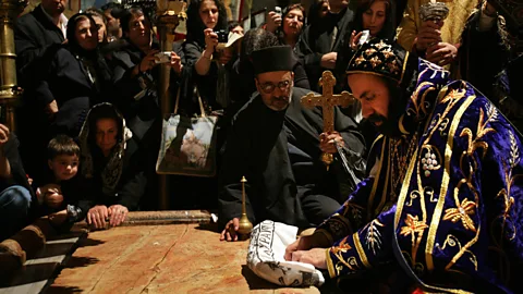 Gali Tibbon/AFP/Getty Images A Syrian Orthodox Archbishop, representing one of the sects that uses the church, prays over the Stone of Unction (Credit: Gali Tibbon/AFP/Getty Images)