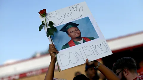 Getty Images A demonstrator holds up a picture of 18-year-old Michael Brown, who was shot and killed by a police officer in Ferguson, Missouri in 2014 (Credit: Getty Images)