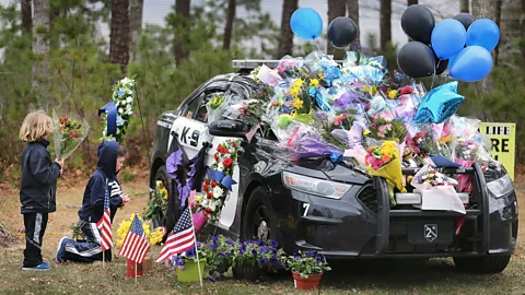 Getty Images Boys leave flowers at the cruiser of Massachussetts police officer Sean Gannon, who was shot and killed in April 2018 while serving a warrant (Credit: Getty Images)